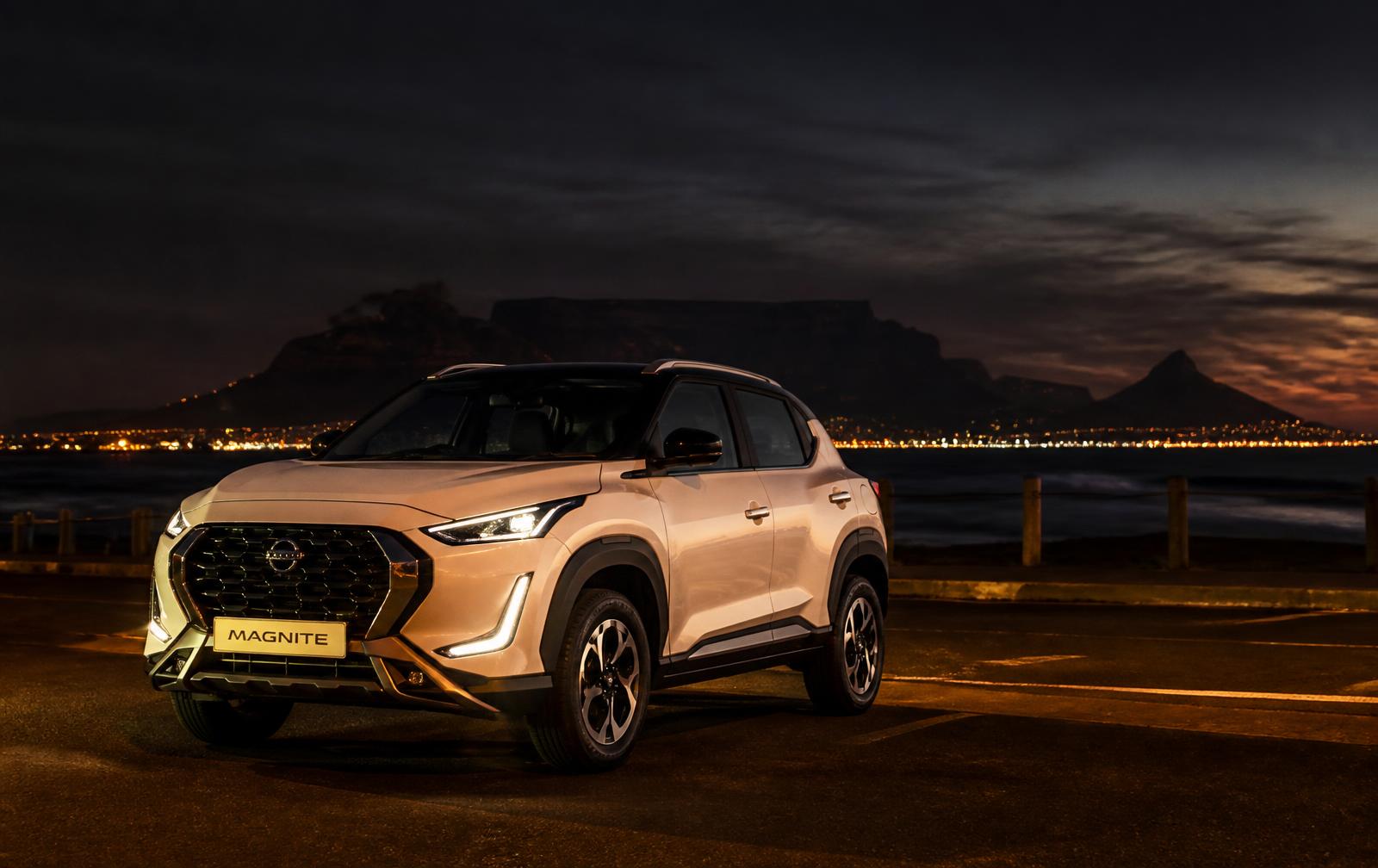 Nissan Magnite parked on a coastal road at night with Table Mountain behind it
